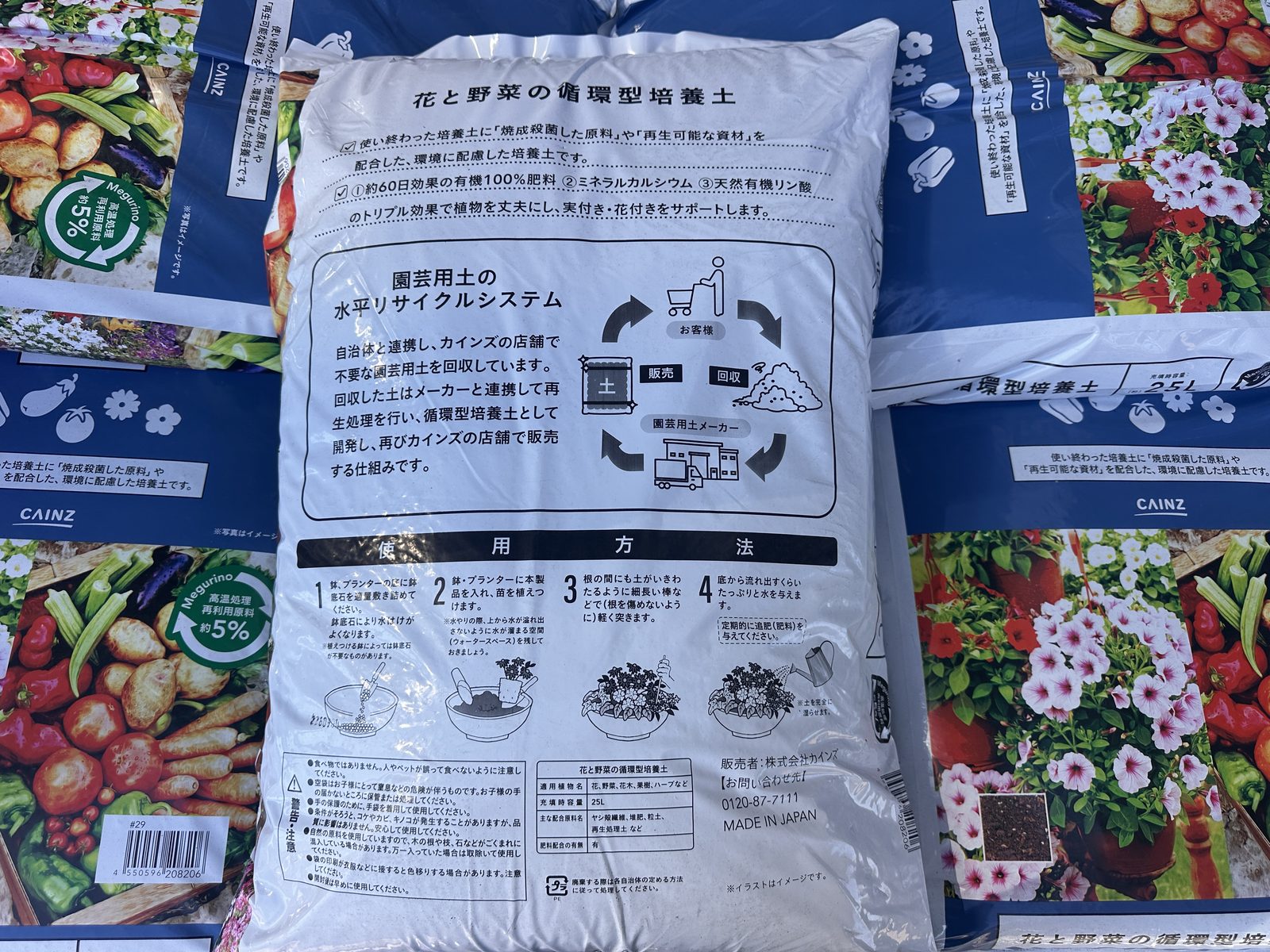 カインズの店頭に並ぶ「花と野菜の循環型培養土」25L の袋の裏。表示欄、約60日効果の有機100%肥料の説明、使い終わった園芸用土を回収して再生する仕組み、使用方法の4手順が印刷されている