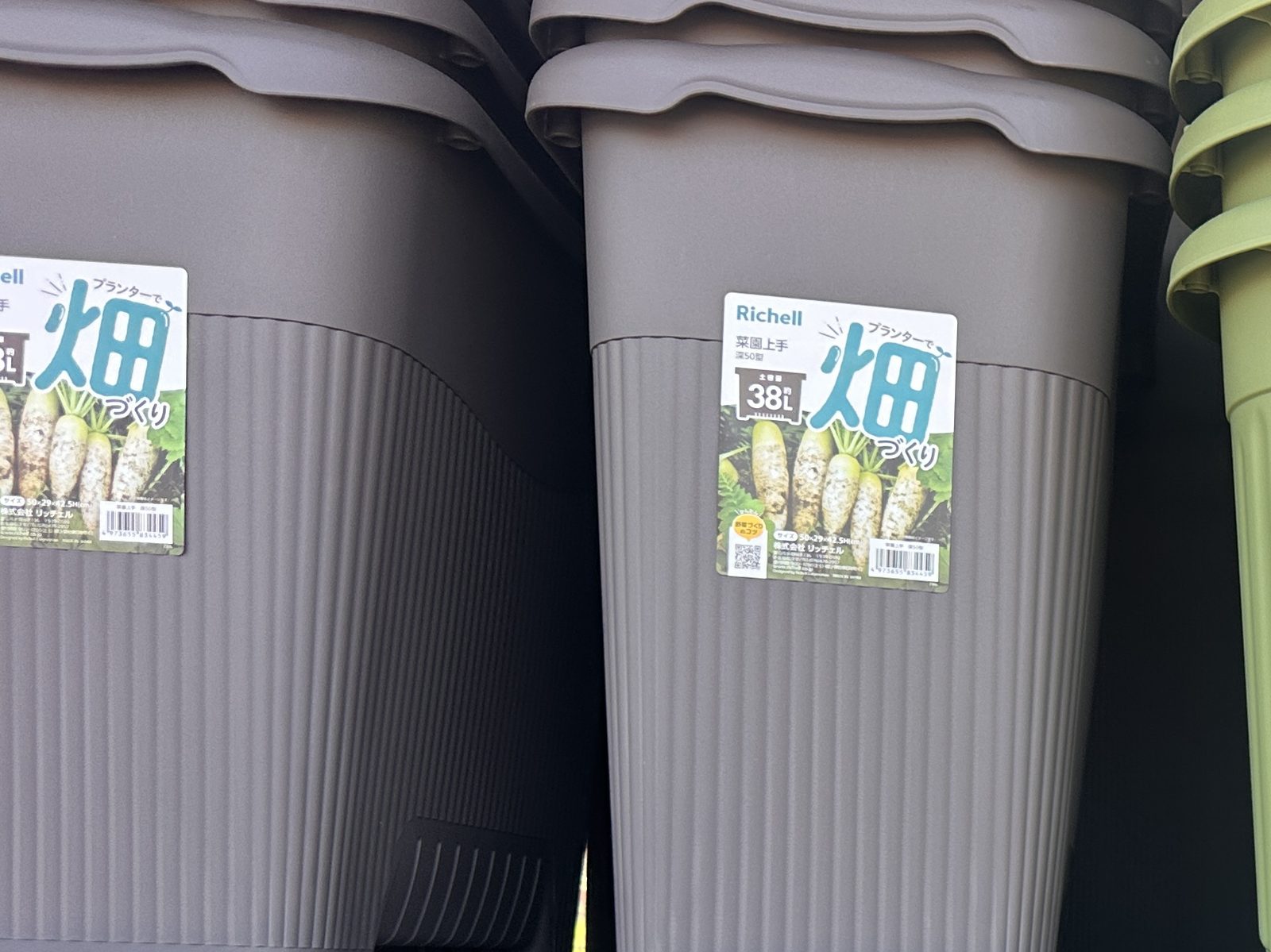 売り場に重ねて並ぶこげ茶色の深型プランター「菜園上手 深50型」。ラベルに「土容量 約38L」と「サイズ 50×29×42.5H(cm)」の表示